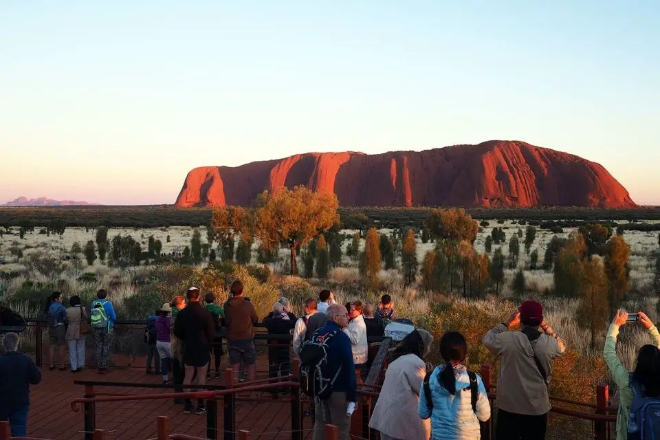 Viajeros toman fotos de Uluru en el territorio del Norte, Australia
