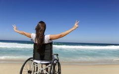 Mujer en silla de ruedas en playa con turismo accesible e incluyente