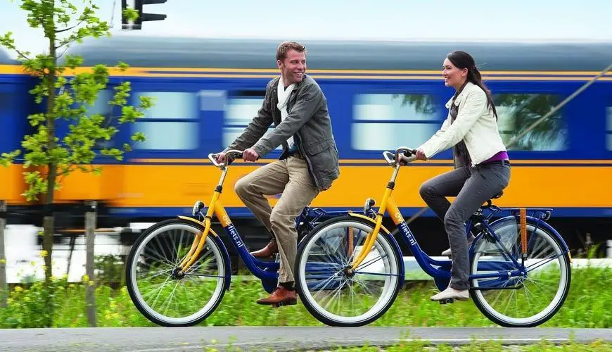Una pareja de ciclistas viajando a lado de un tren