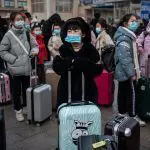 Grupo de viajeras de origen asiático usando tapabocas en un aeropuerto