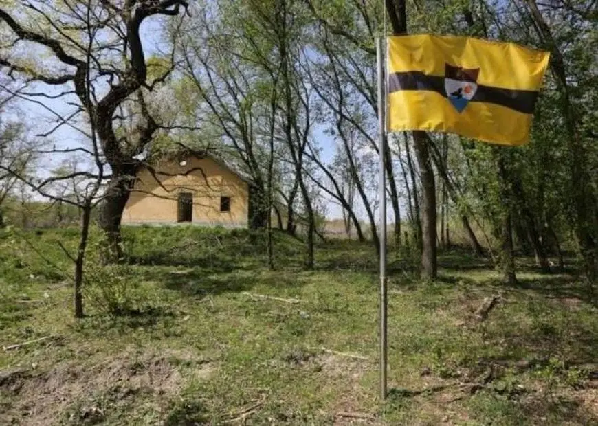 Cabaña abandonada capital de Liberland con su bandera al frente