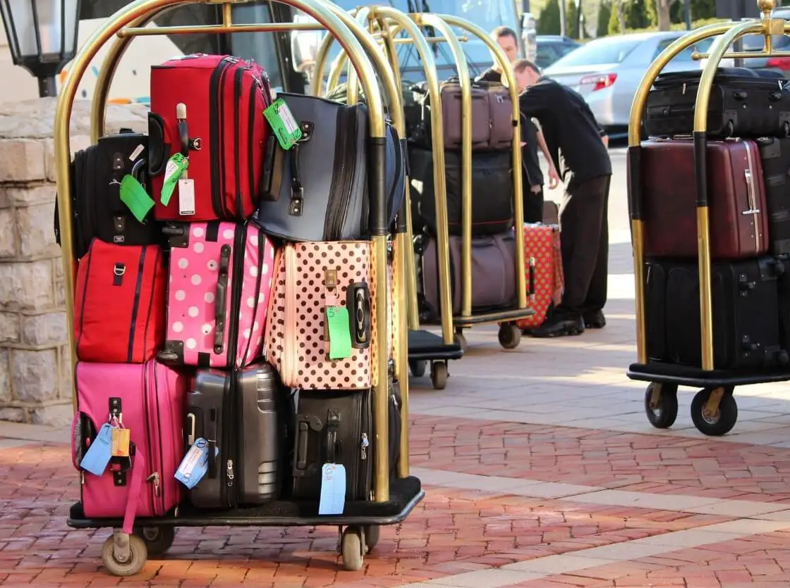Carrito de hotel cargado de maletas de colores