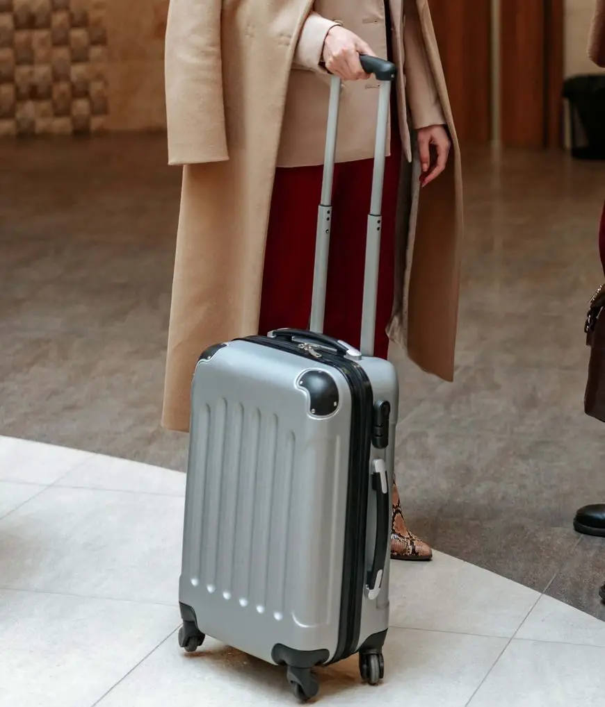 Mujer sosteniendo el asa de una maleta rígida